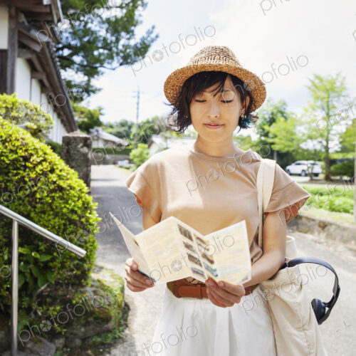 Japanese woman wearing hat and holding map standing outside Buddhist temple. Japanese woman wearing hat and holding map standing outside Buddhist temple.