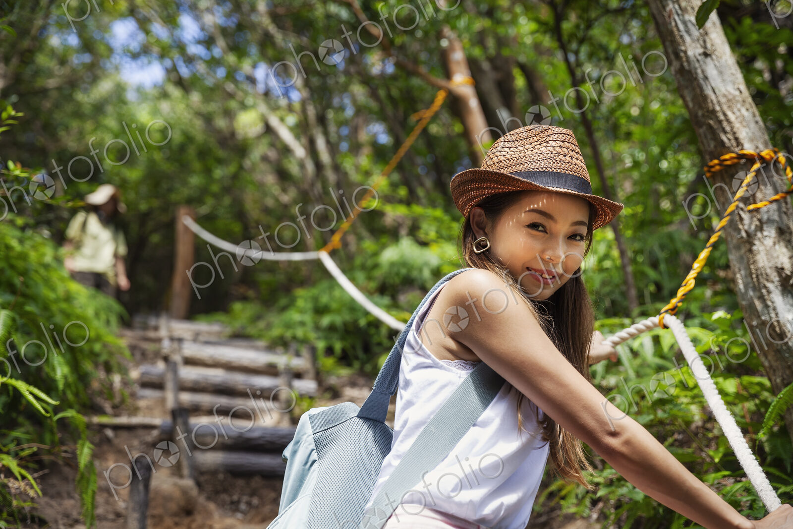 Japanese woman wearing hat hiking in a forest.