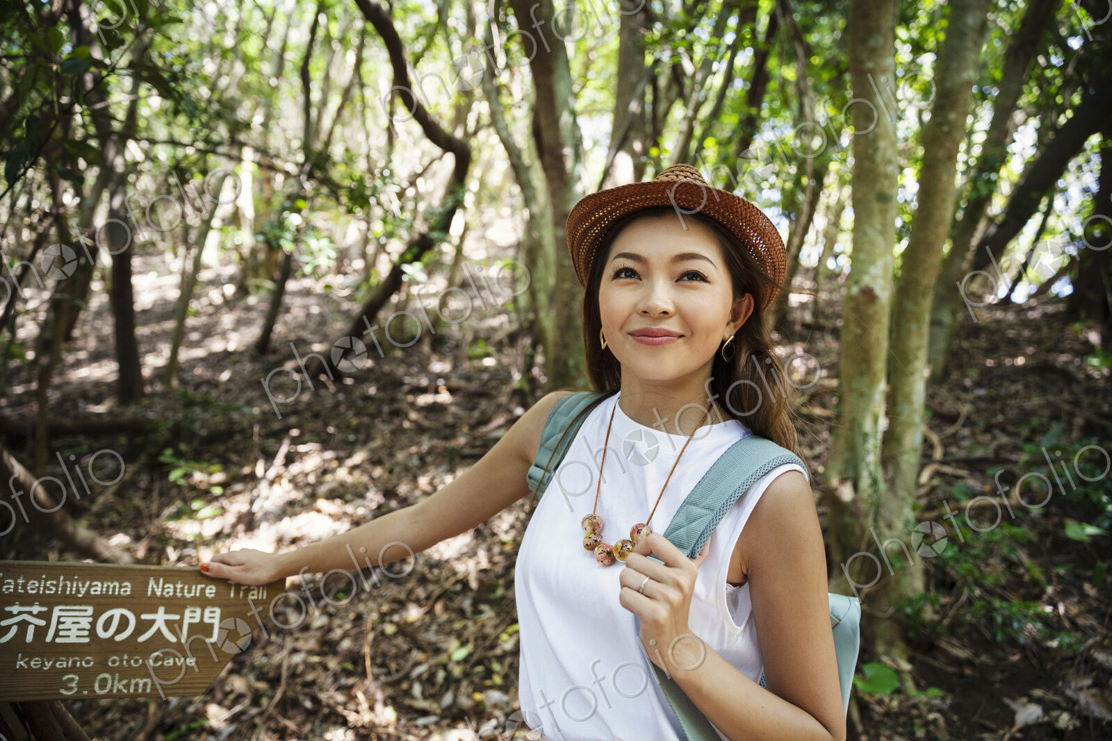 Japanese woman wearing hat hiking in a forest.