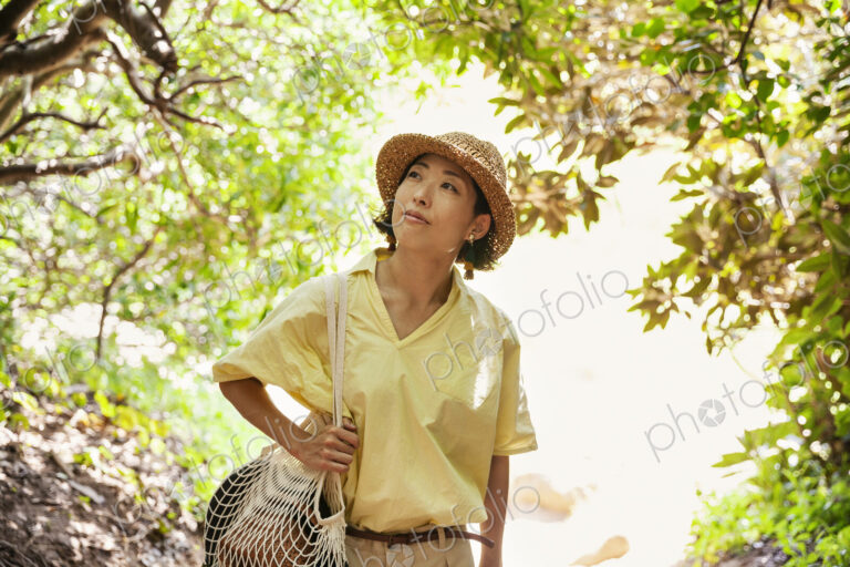 Japanese woman wearing hat hiking in a forest.