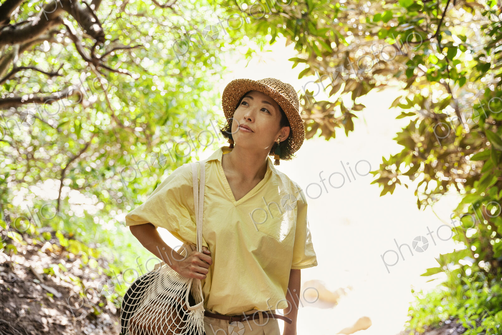 Japanese woman wearing hat hiking in a forest.