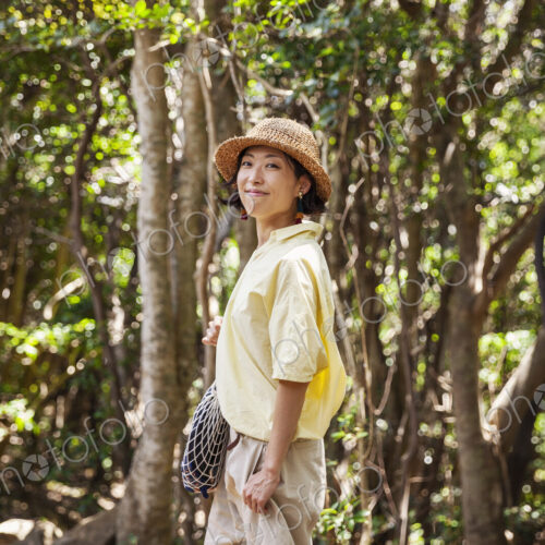 Japanese woman wearing hat hiking in a forest. Japanese woman wearing hat hiking in a forest.