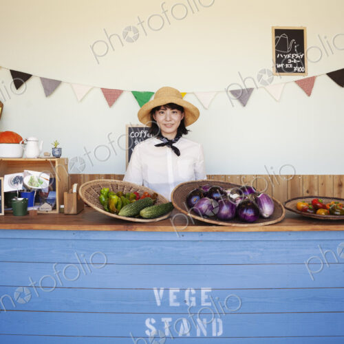 Japanese woman wearing hat standing behind counter in a farm shop, smiling at camera. Japanese woman wearing hat standing behind counter in a farm shop, smiling at camera.
