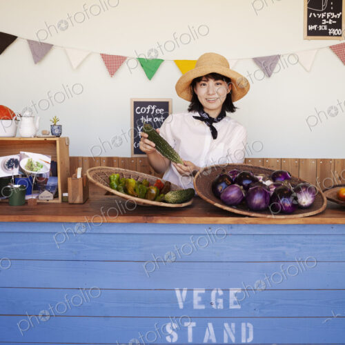 Japanese woman wearing hat standing behind counter in a farm shop, smiling at camera. Japanese woman wearing hat standing behind counter in a farm shop, smiling at camera.