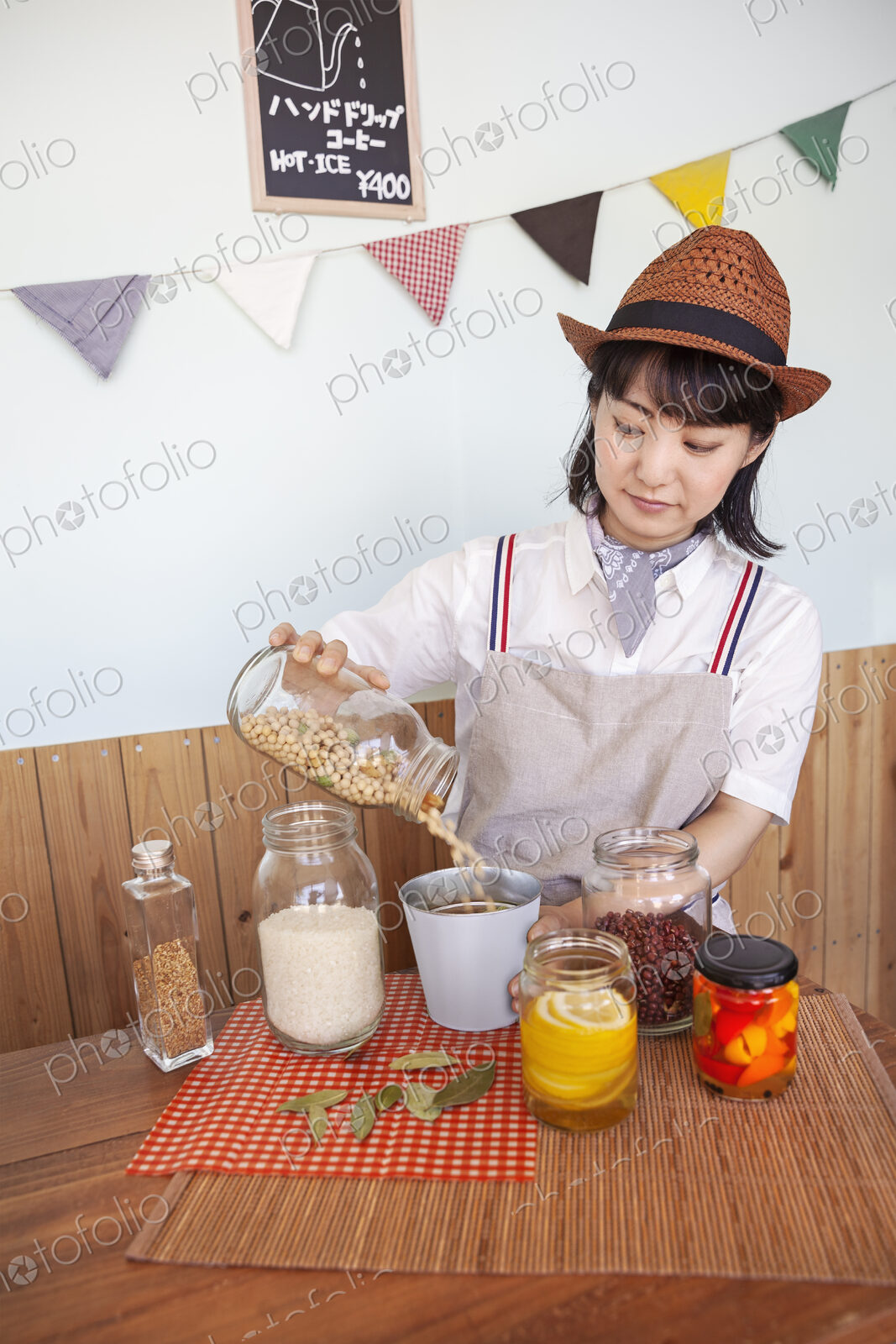 Japanese woman wearing hat standing in a farm shop with a selection of foods and…