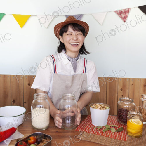 Japanese woman wearing hat standing in a farm shop with a selection of foods and…
