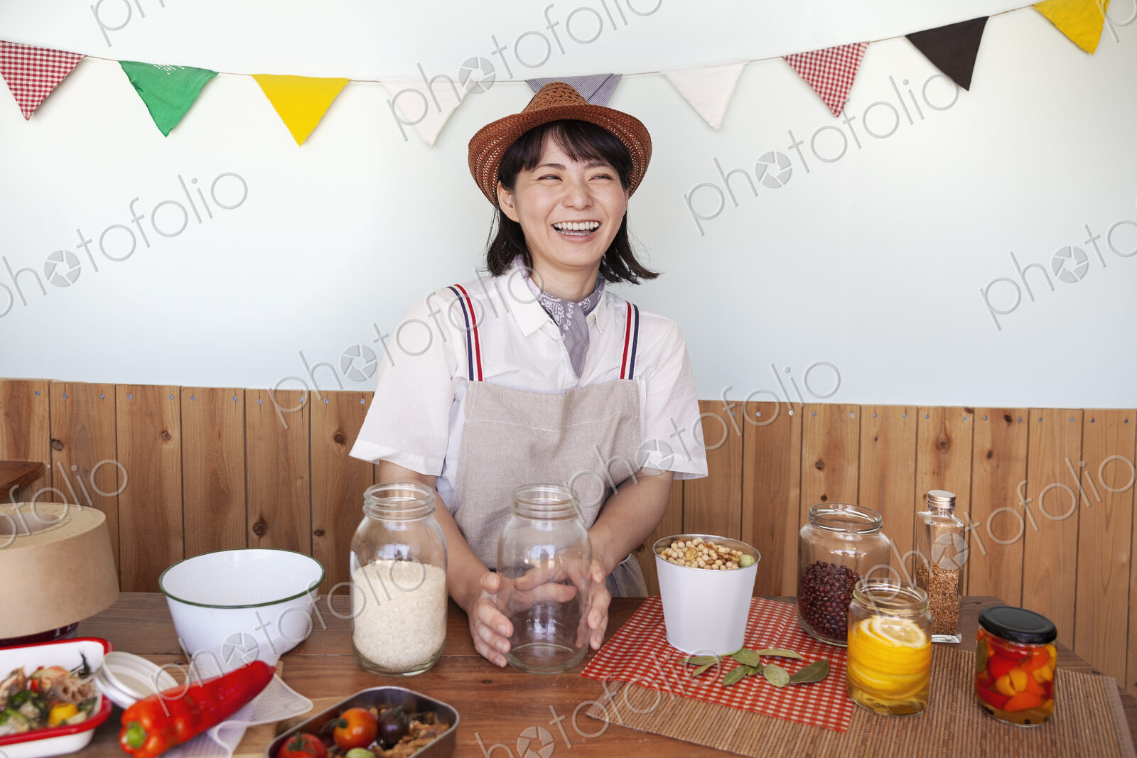 Japanese woman wearing hat standing in a farm shop with a selection of foods and…