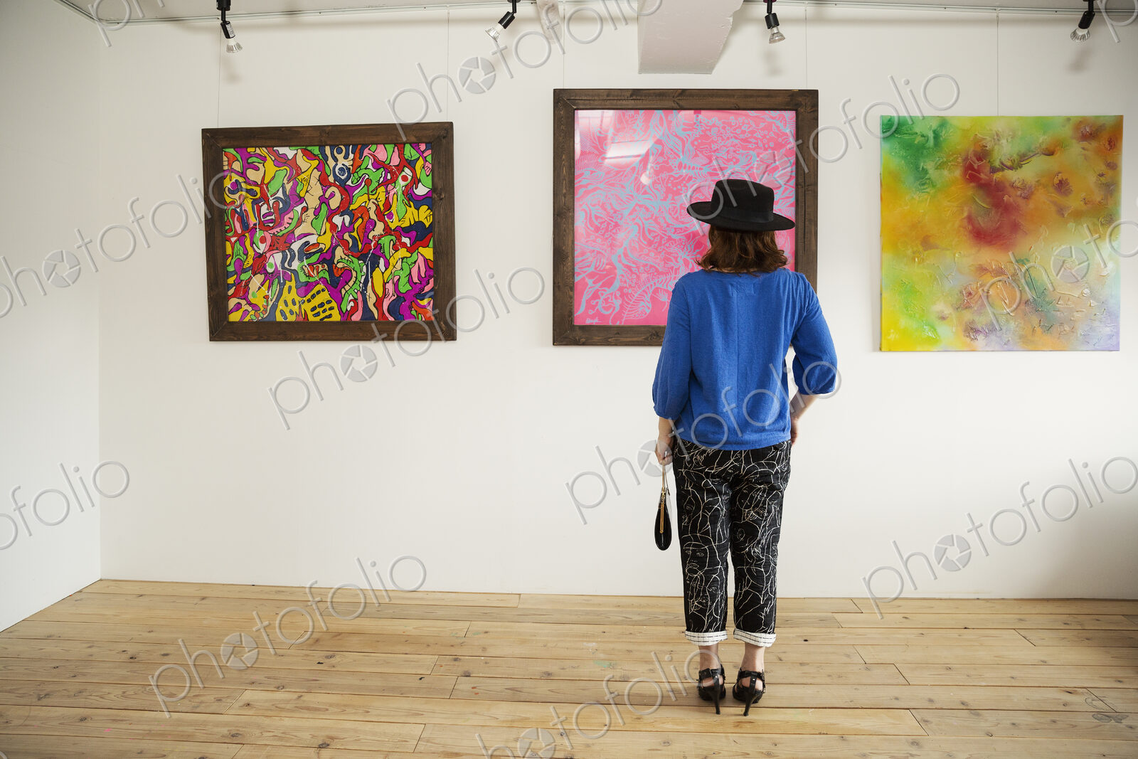 Japanese woman wearing hat standing in front of abstract painting in an art gallery.