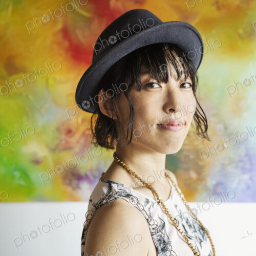 Japanese woman wearing hat standing in front of abstract painting in an art gallery.