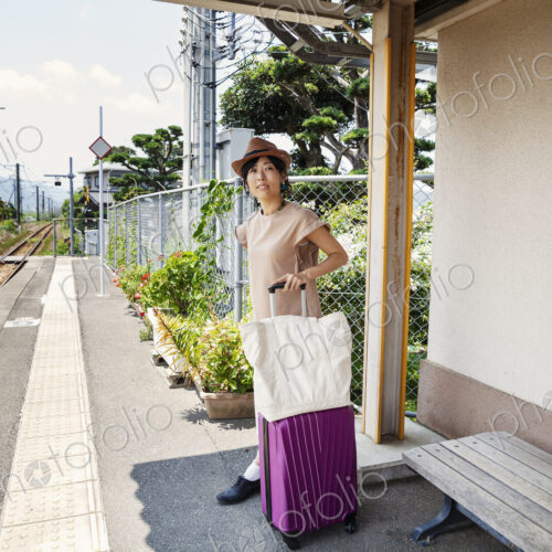 Japanese woman wearing hat standing on railway station platform with shopping bag and… Japanese woman wearing hat standing on railway station platform with shopping bag and…