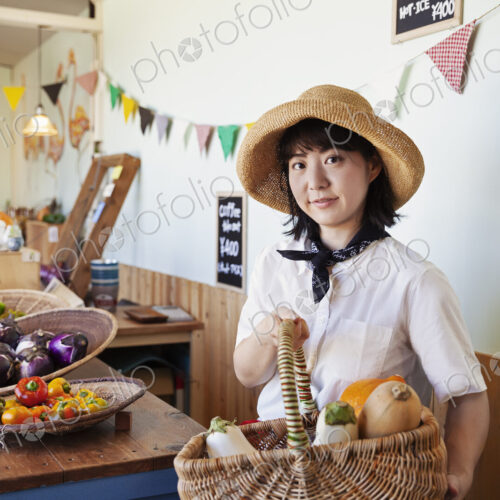 Japanese woman wearing hat working in a farm shop, smiling at camera. Japanese woman wearing hat working in a farm shop, smiling at camera.