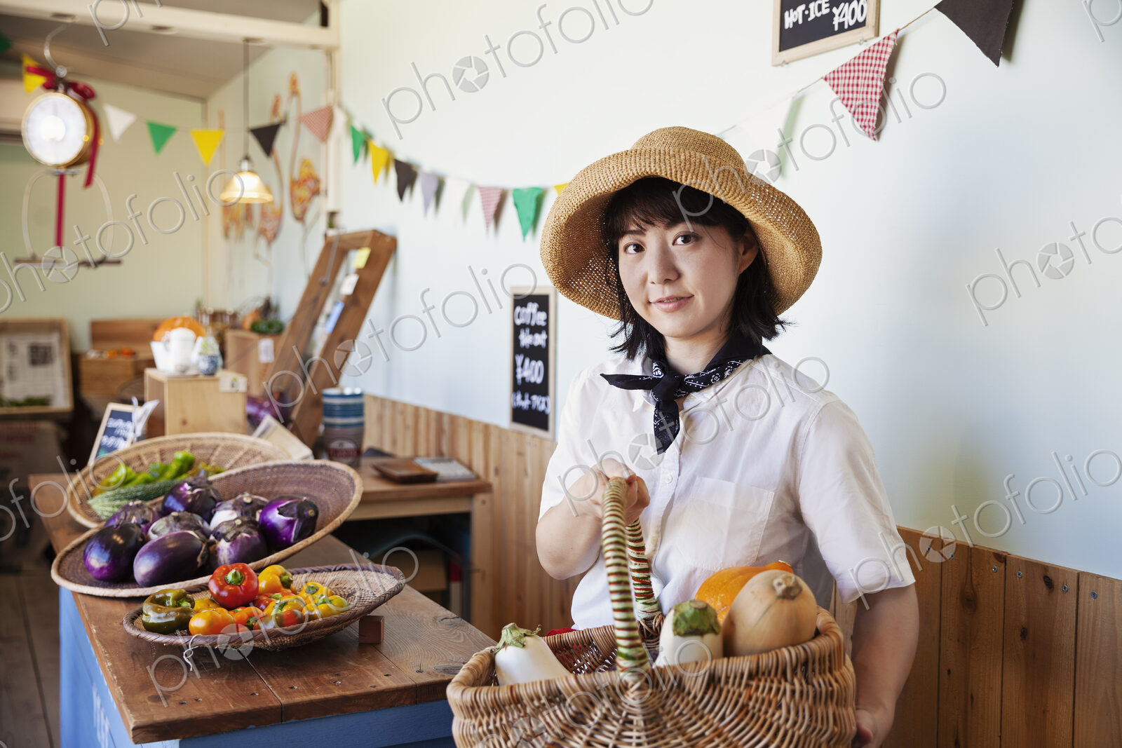 Japanese woman wearing hat working in a farm shop, smiling at camera.