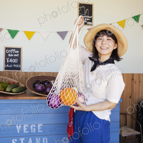 Japanese woman wearing hat working in a farm shop, smiling at camera. Japanese woman wearing hat working in a farm shop, smiling at camera.