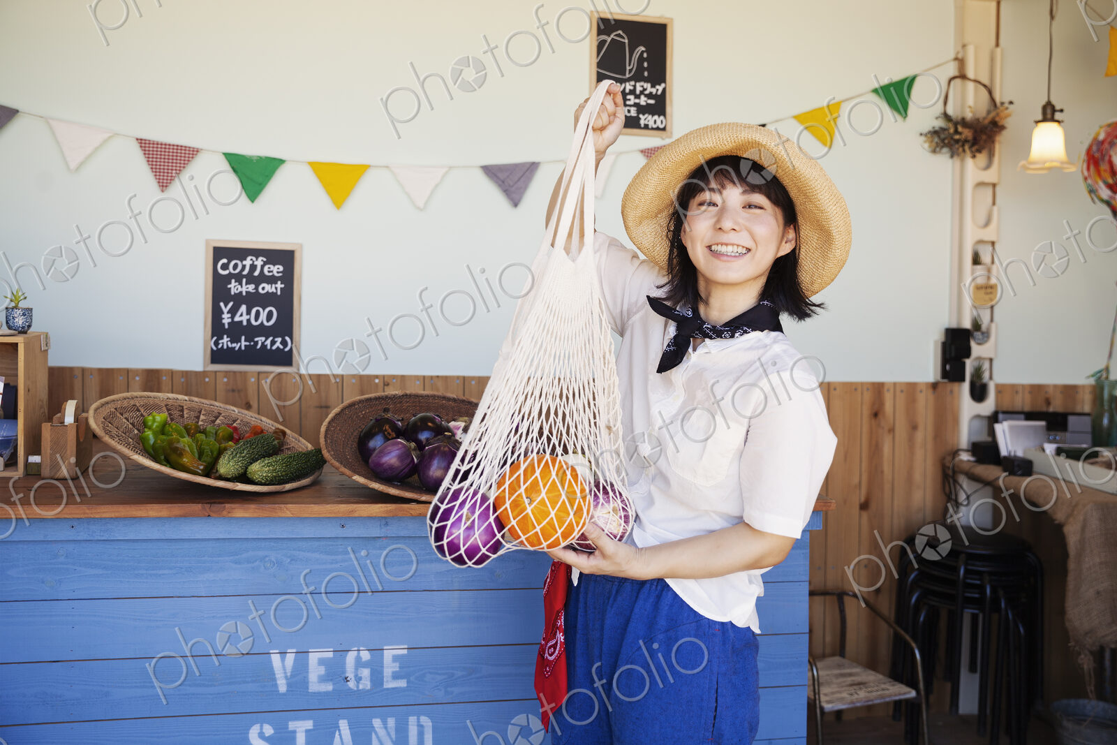 Japanese woman wearing hat working in a farm shop, smiling at camera.