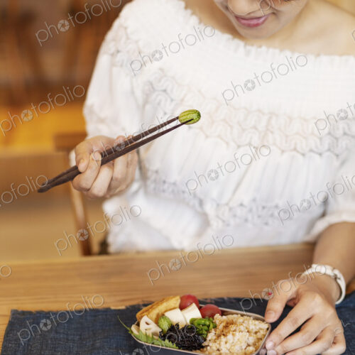 Japanese women eating with chopsticks in a vegetarian cafe. Japanese women eating with chopsticks in a vegetarian cafe.