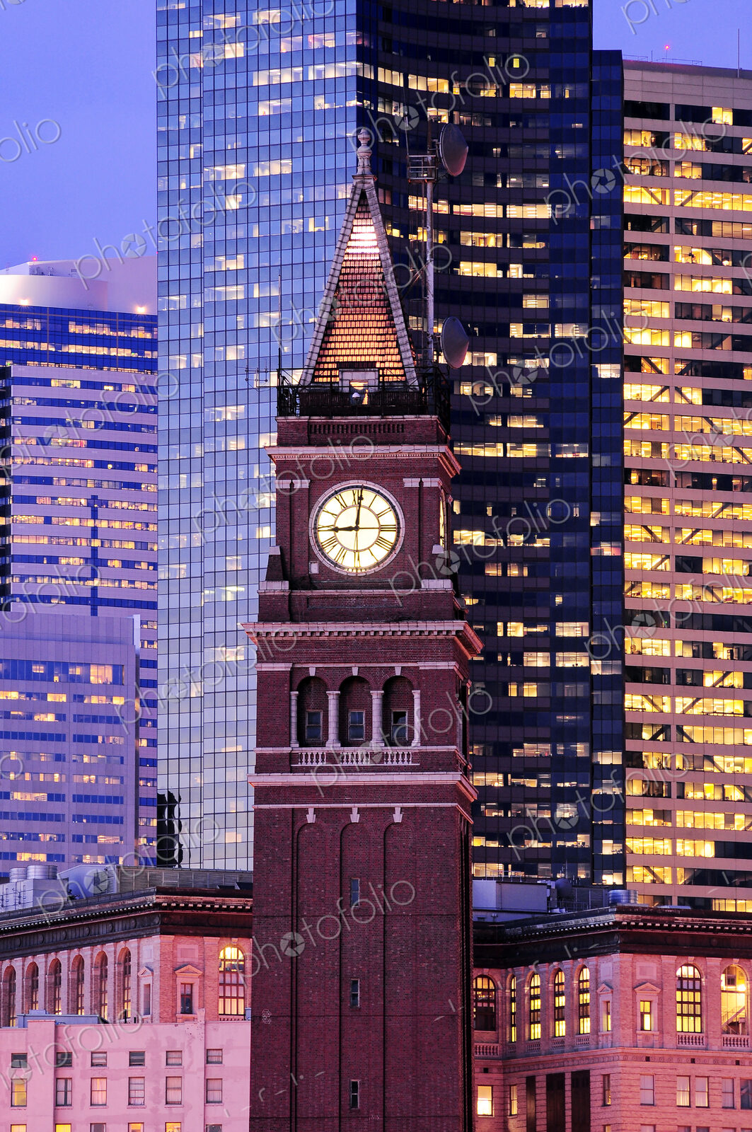 King street station clock, among tall skyscrapers in Seattle at dusk.