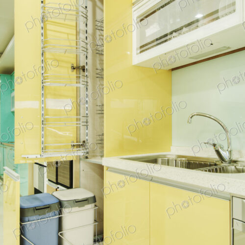 Kitchen cupboard with stainless steel metal racking, built in waste bins, yellow doors.