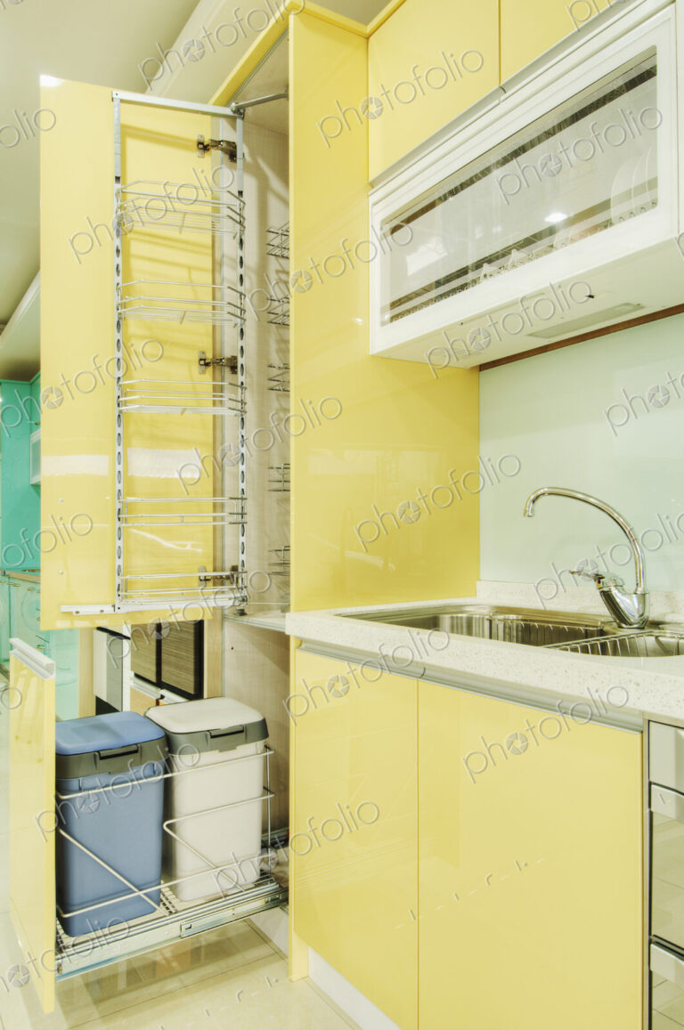Kitchen cupboard with stainless steel metal racking, built in waste bins, yellow doors.
