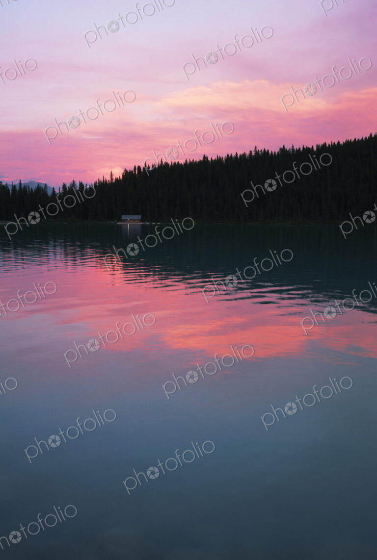 Lake Louise with reflections of pink sky at sunset.