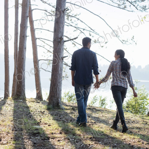 Lakeside. A couple walking in the shade of pine trees in summer. Lakeside. A couple walking in the shade of pine trees in summer.