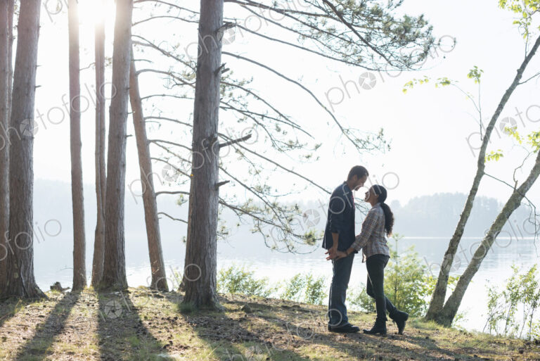 Lakeside. A couple walking in the shade of pine trees in summer.