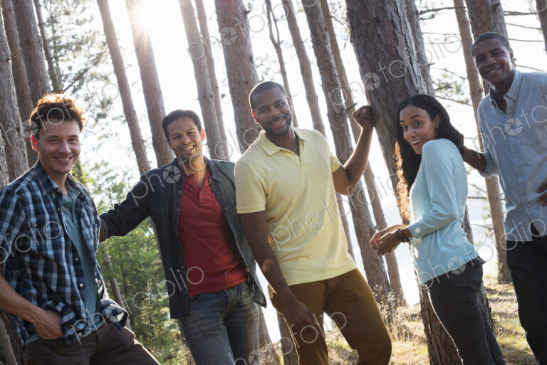 Lakeside. A group of people, friends gathered in the shade of pine trees in summer.