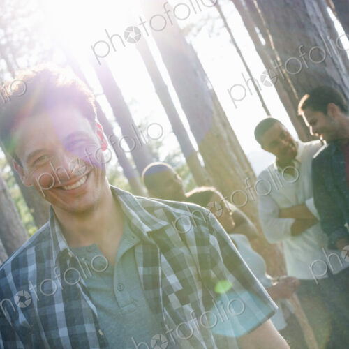 Lakeside. A group of people, friends gathered in the shade of pine trees in summer.