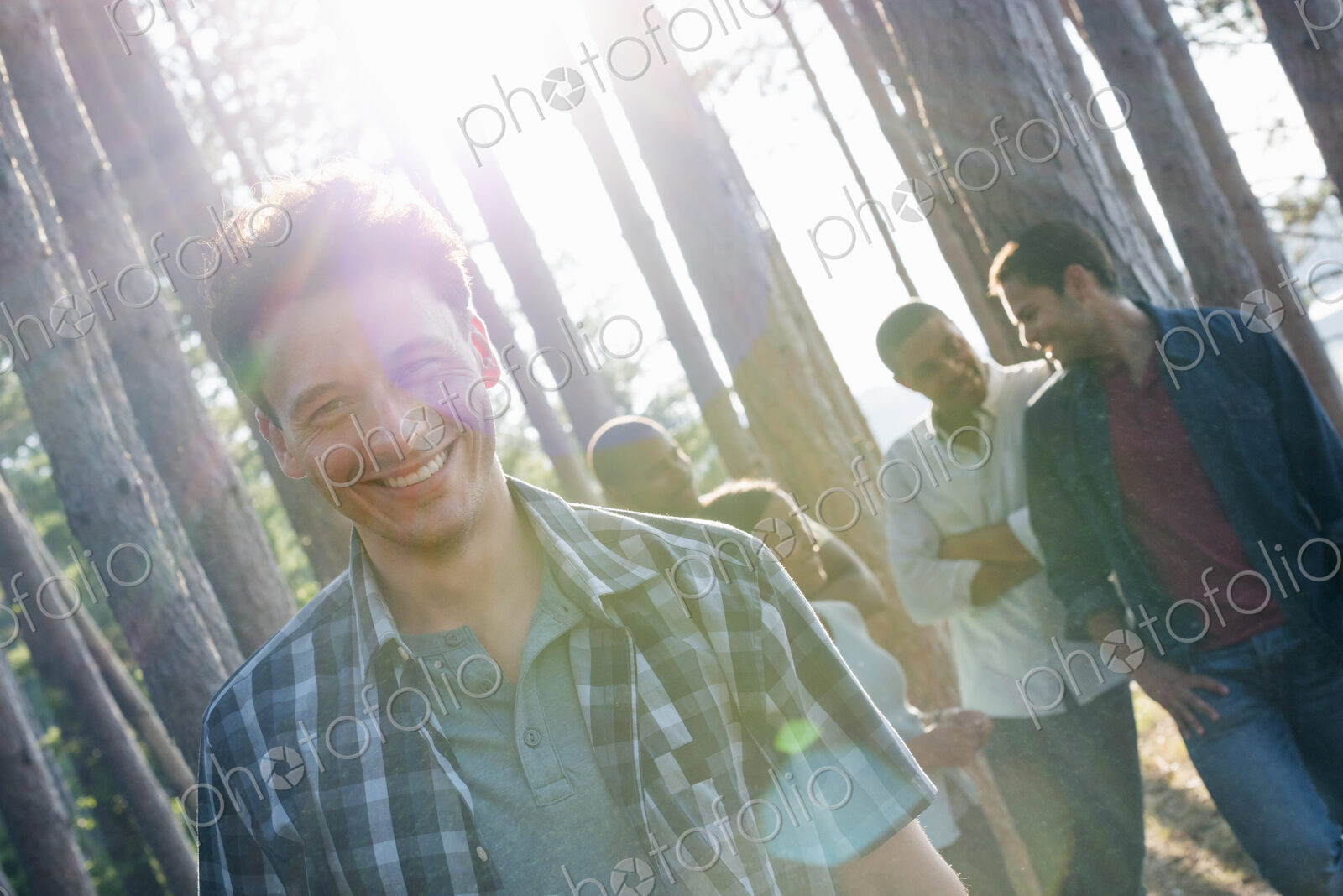 Lakeside. A group of people, friends gathered in the shade of pine trees in summer.