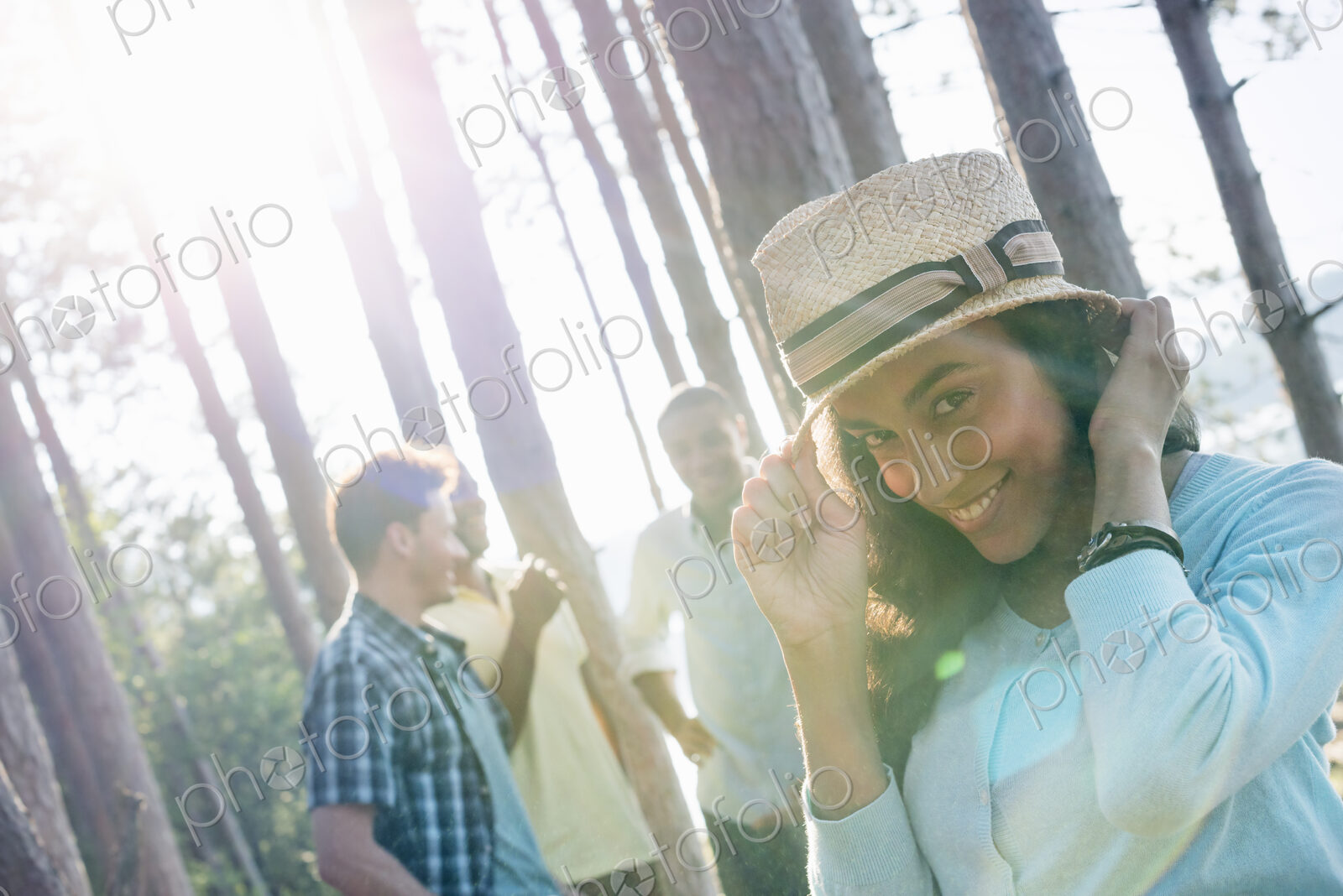 Lakeside. A group of people, friends gathered in the shade of pine trees in summer.