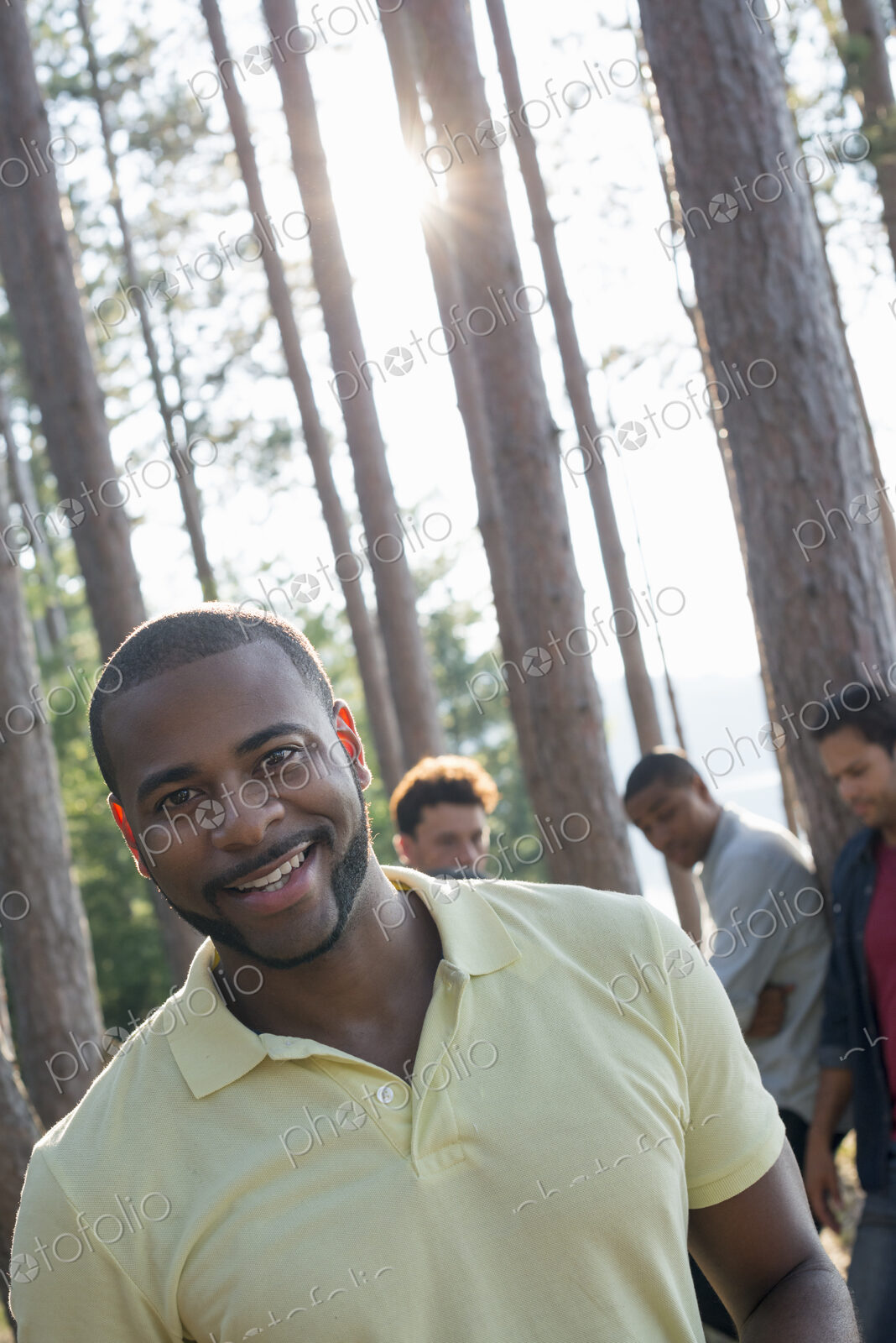 Lakeside. A group of people, friends gathered in the shade of pine trees in summer.