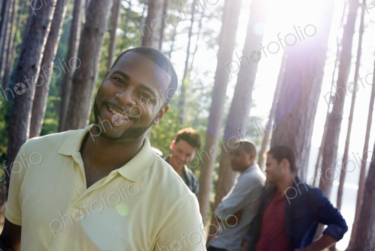 Lakeside. A group of people, friends gathered in the shade of pine trees in summer.