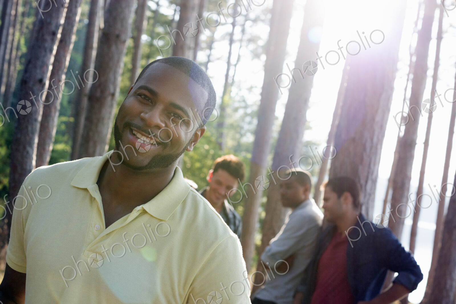 Lakeside. A group of people, friends gathered in the shade of pine trees in summer.
