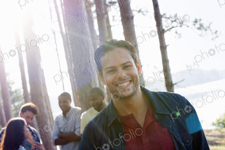 Lakeside. A group of people, friends gathered in the shade of pine trees in summer.
