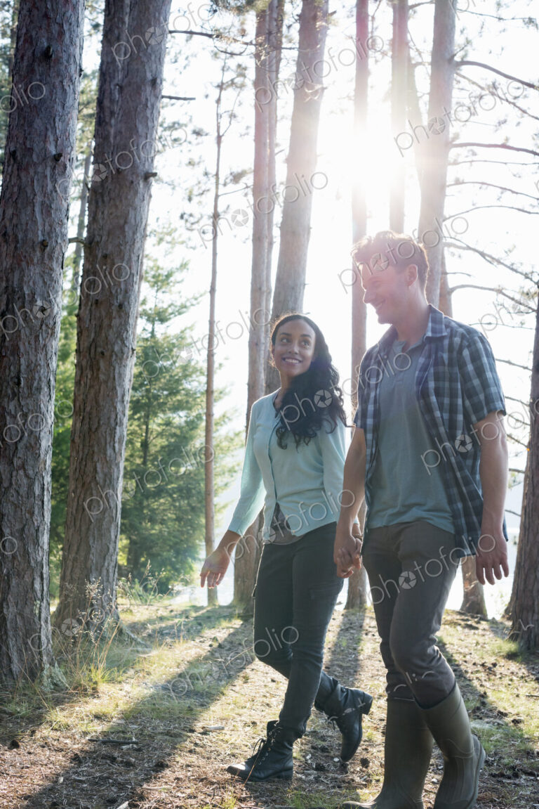 Lakeside. Two people walking in the shade of pine trees in summer.