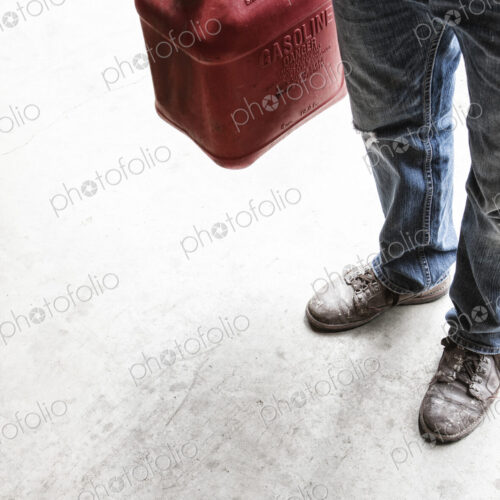 Landscape company employee standing in the company shop with a gas can in his hand. Landscape company employee standing in the company shop with a gas can in his hand.