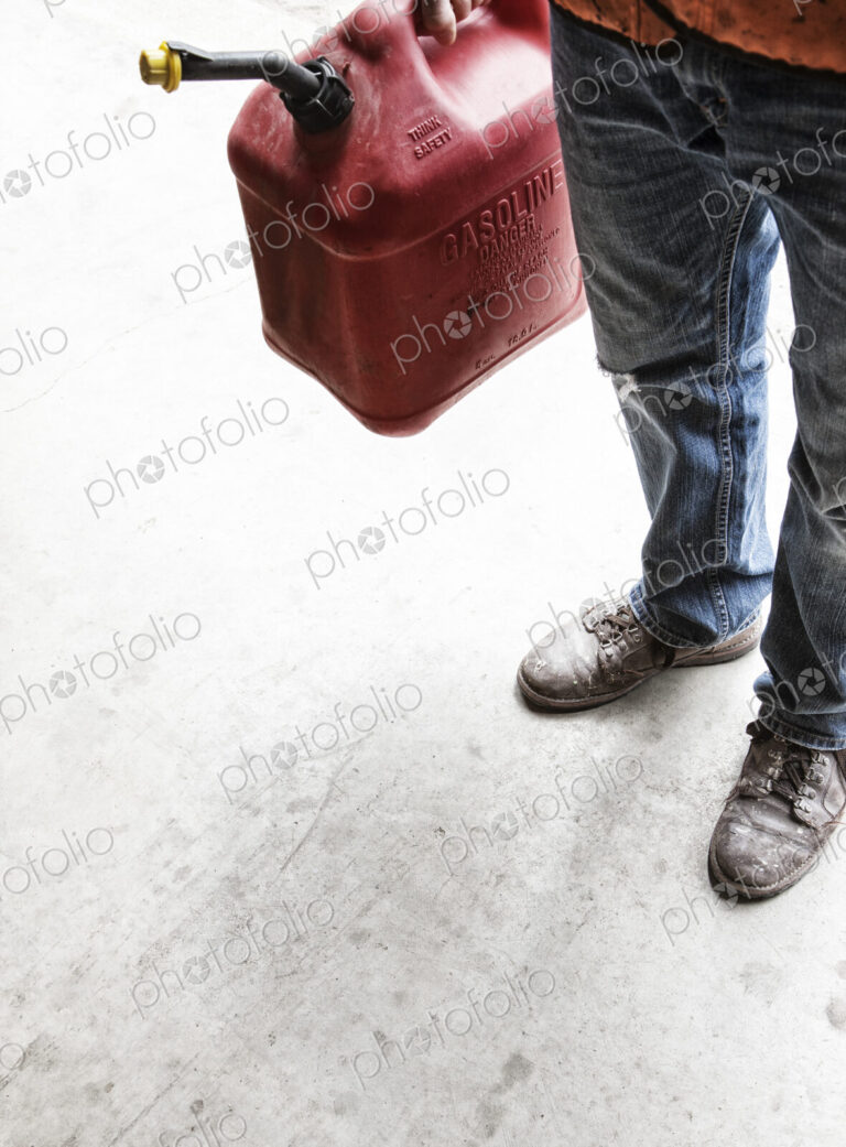 Landscape company employee standing in the company shop with a gas can in his hand.