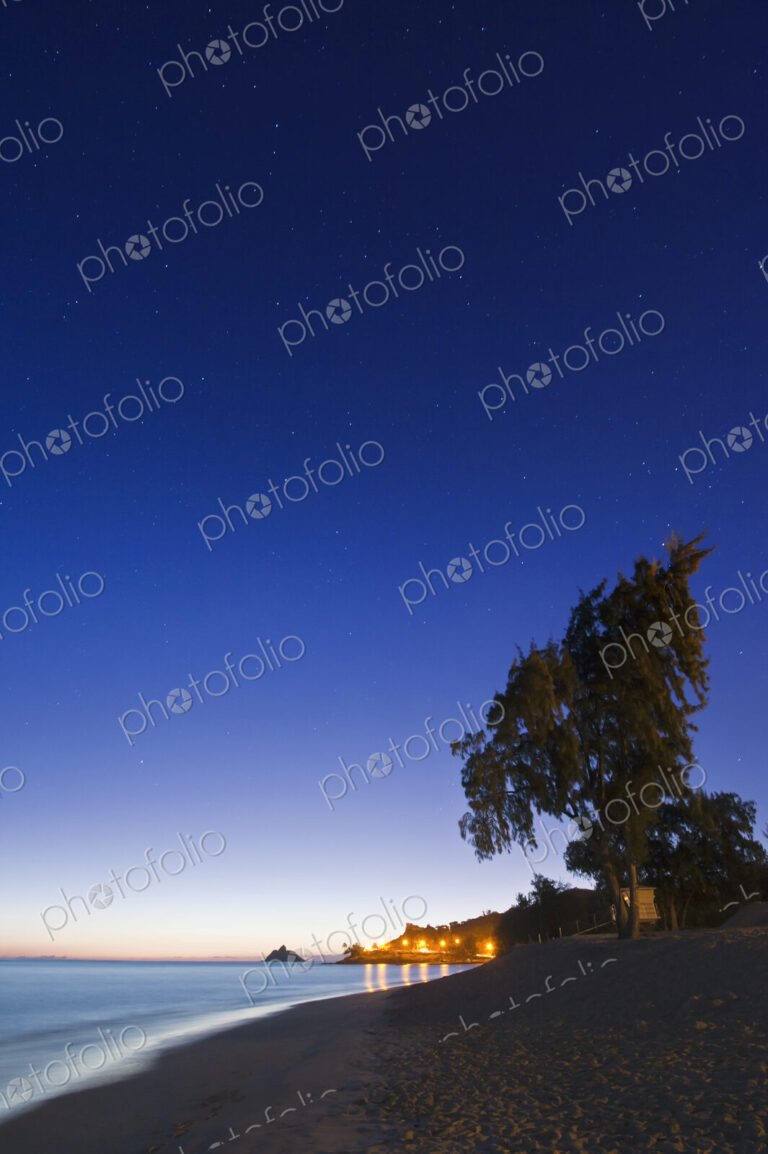 Lanikai Beach at dawn, view along the beach, trees and coastline.