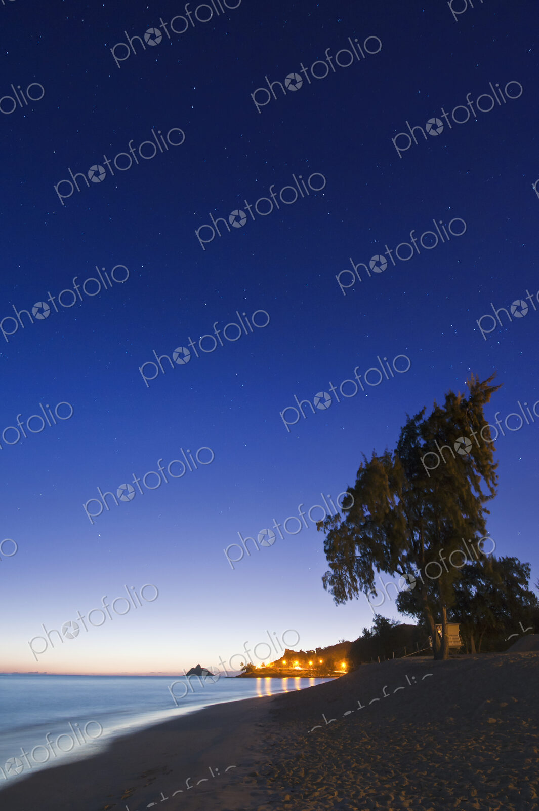 Lanikai Beach at dawn, view along the beach, trees and coastline.