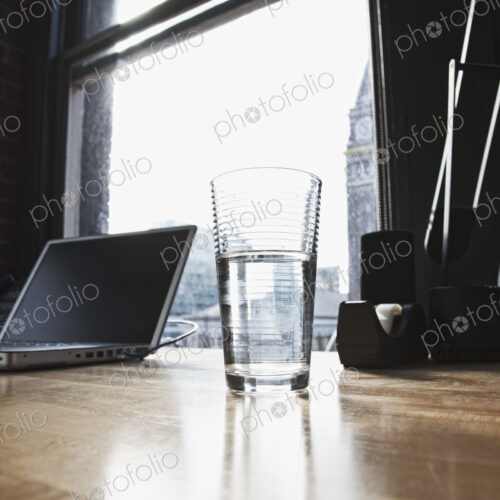 Laptop and drinking water glass on desk in urban office. Laptop and drinking water glass on desk in urban office.