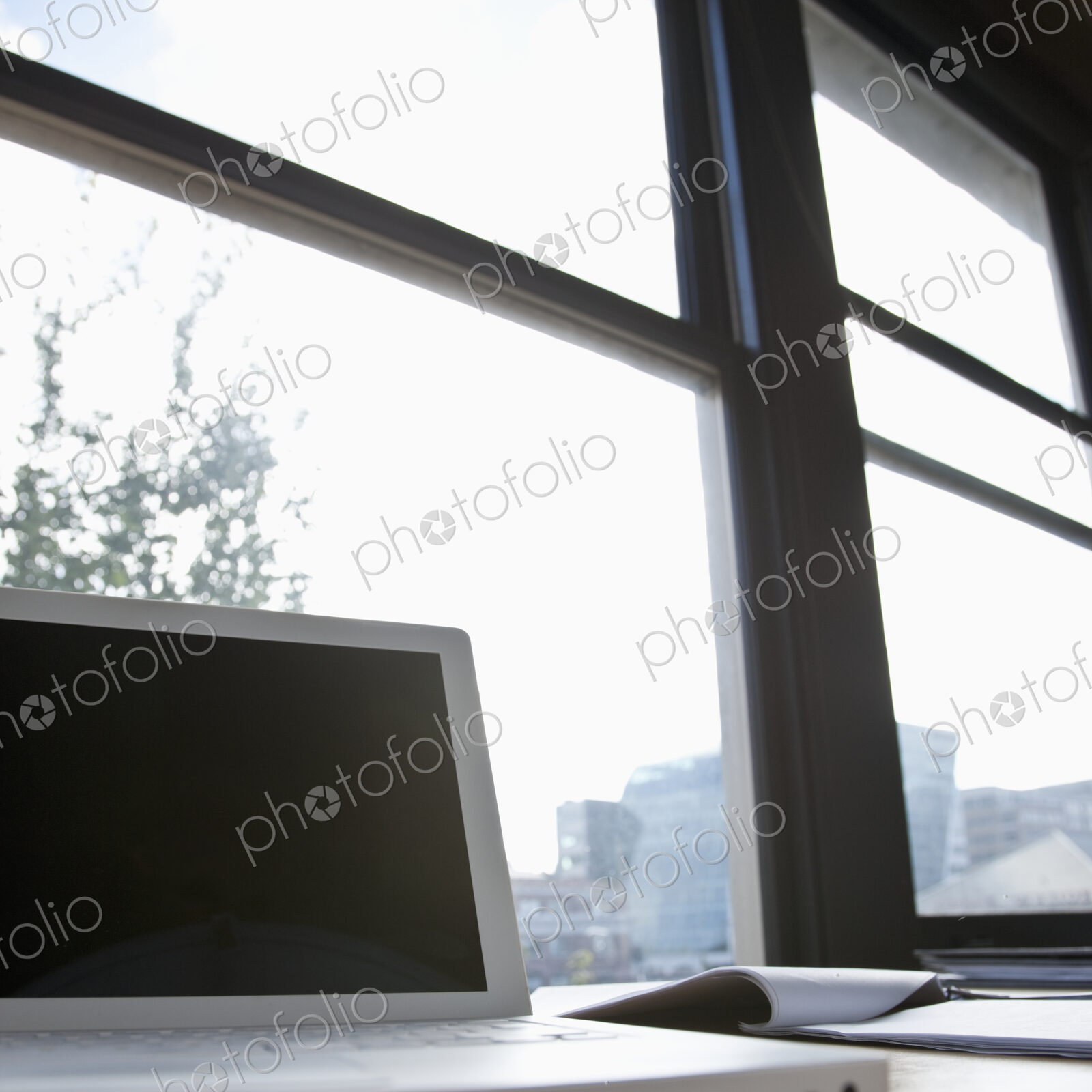 Laptop in front of window on urban skyline.