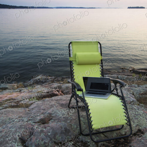 Laptop on lawn chair near remote river