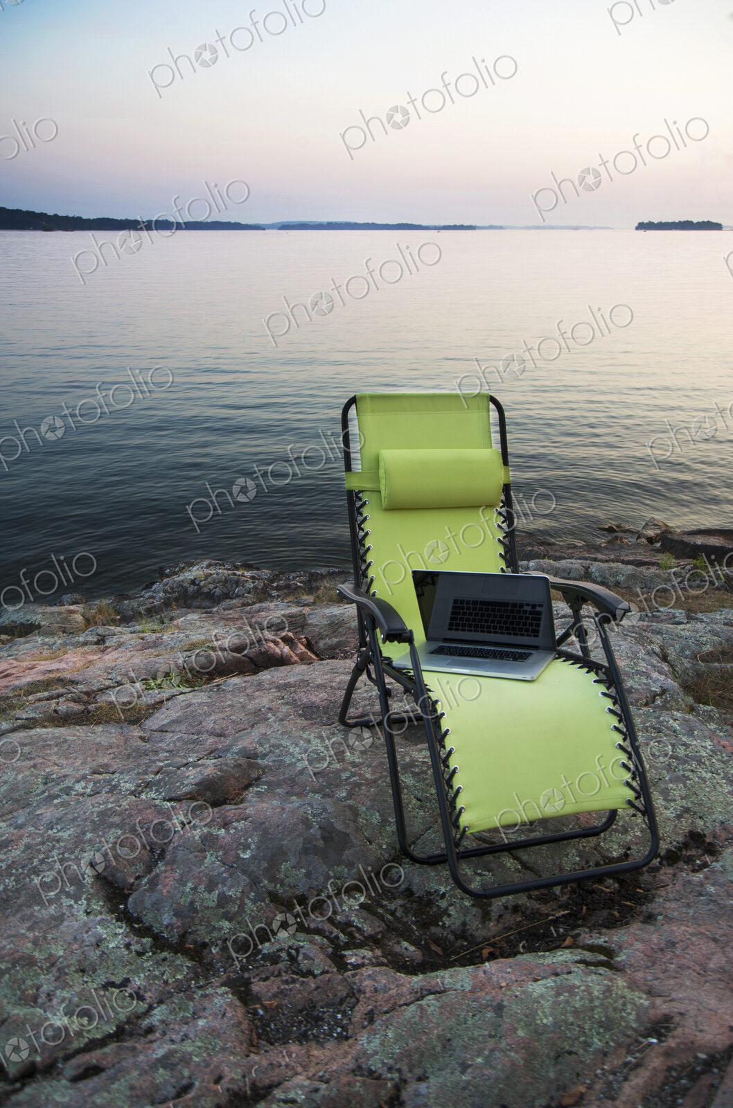 Laptop on lawn chair near remote river