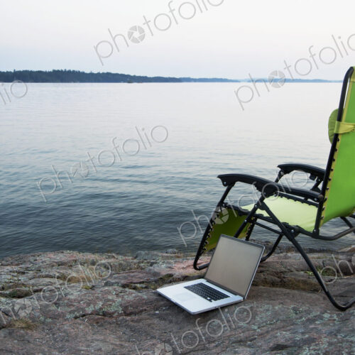 Laptop on lawn chair near remote river Laptop on lawn chair near remote river