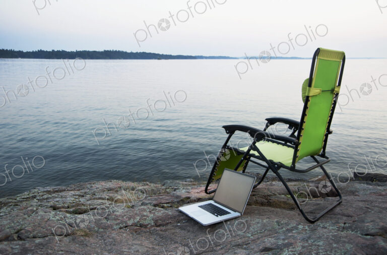 Laptop on lawn chair near remote river