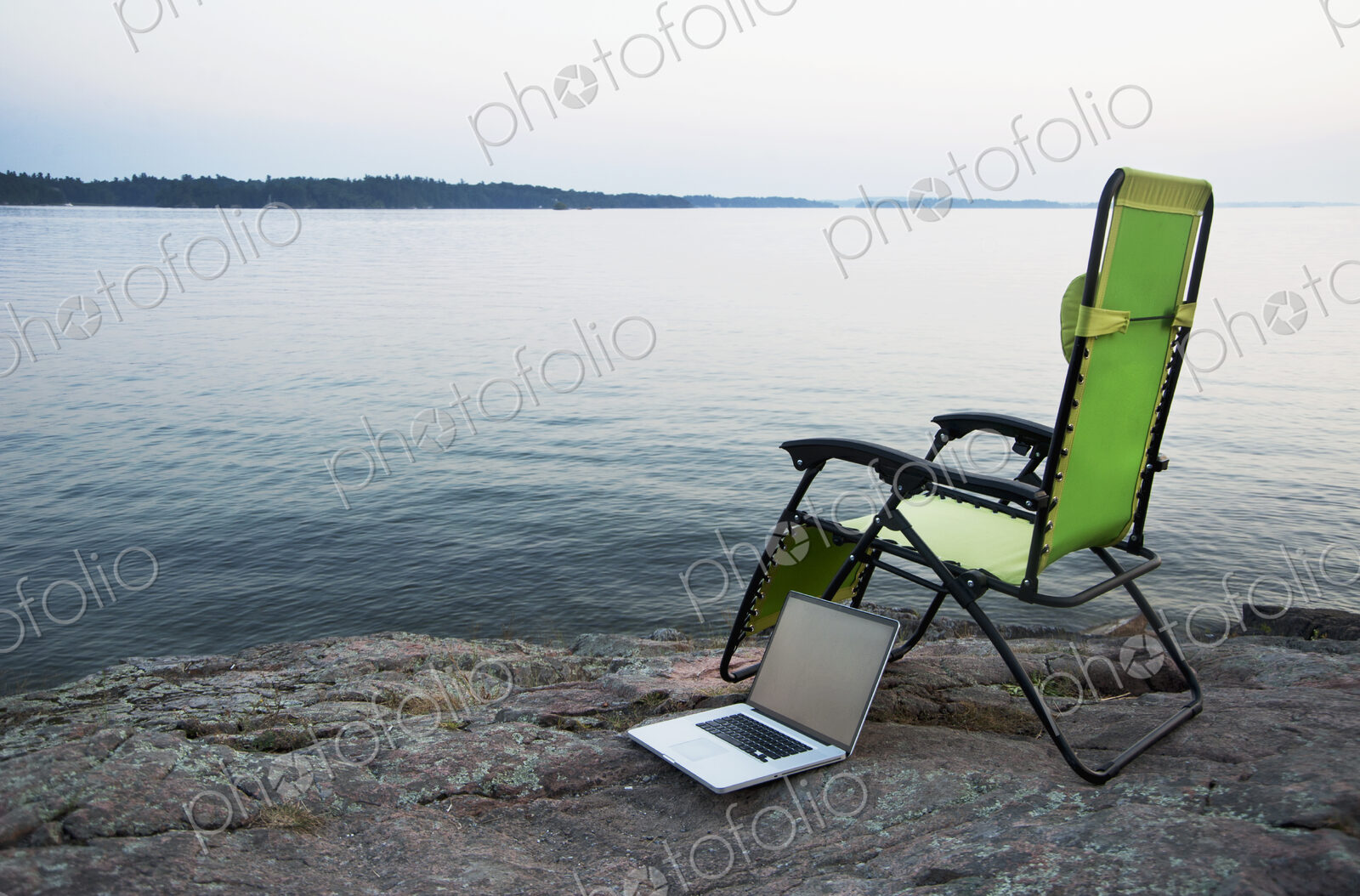 Laptop on lawn chair near remote river