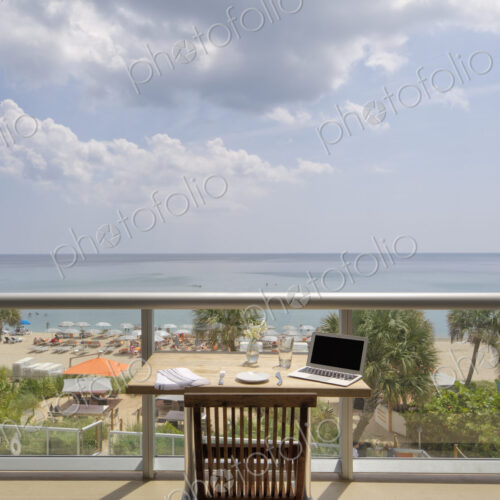 Laptop on restaurant balcony table overlooking beach Laptop on restaurant balcony table overlooking beach