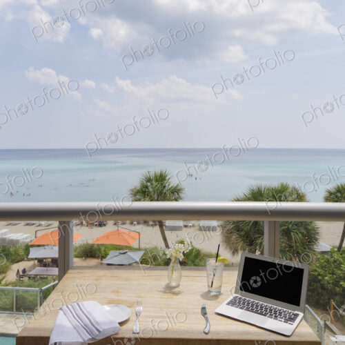Laptop on restaurant balcony table overlooking beach Laptop on restaurant balcony table overlooking beach