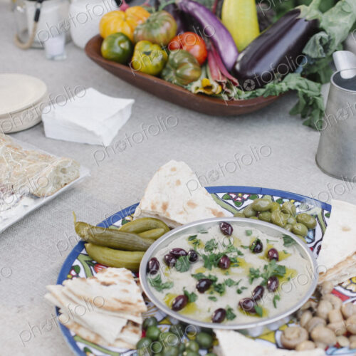 Large bowl of vegetables, dips and bread on a table in a garden. Large bowl of vegetables, dips and bread on a table in a garden.