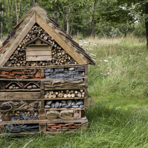 Large bug house with several layers of different materials in a garden.