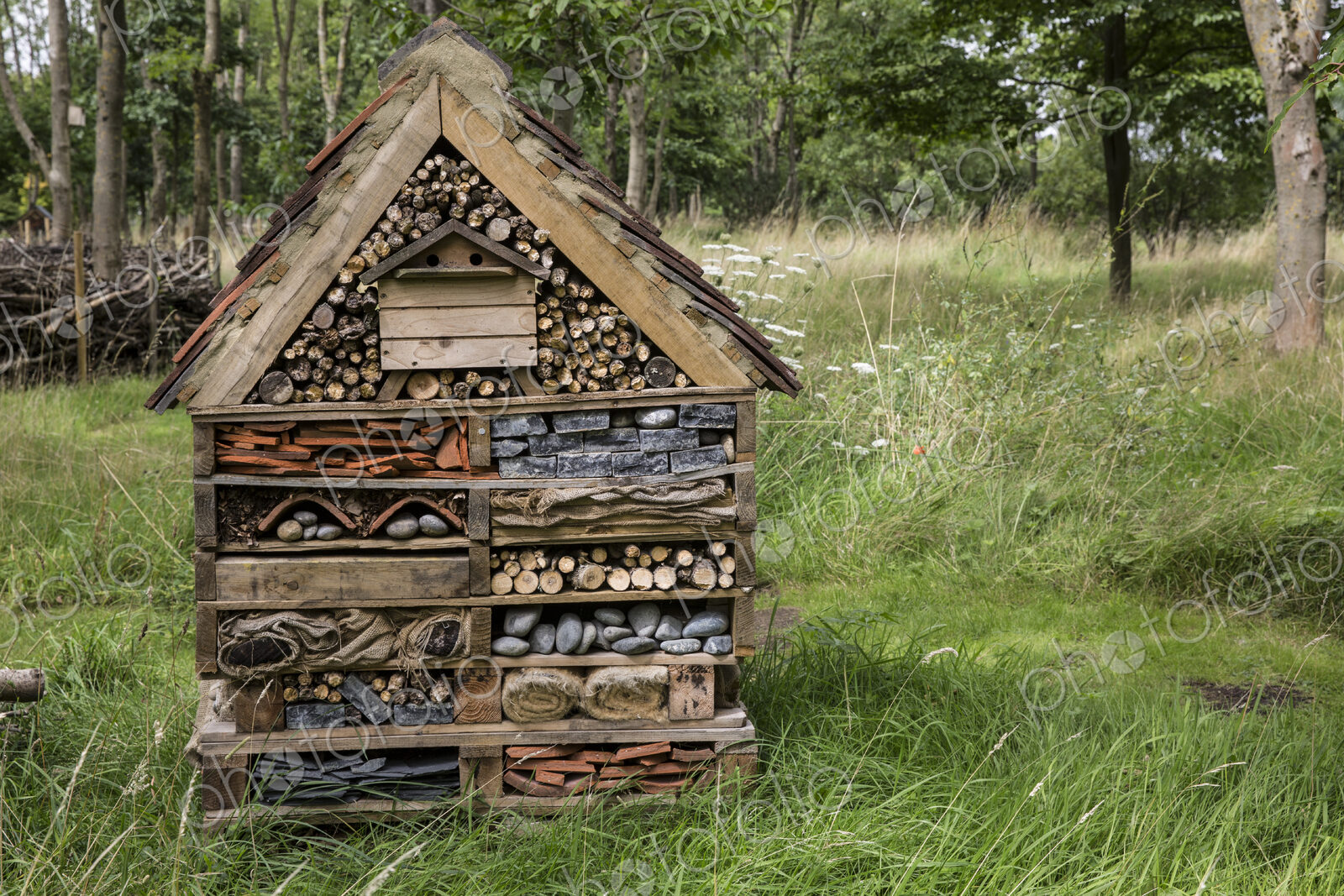 Large bug house with several layers of different materials in a garden.